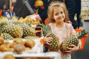girl in grocery store with pineapples