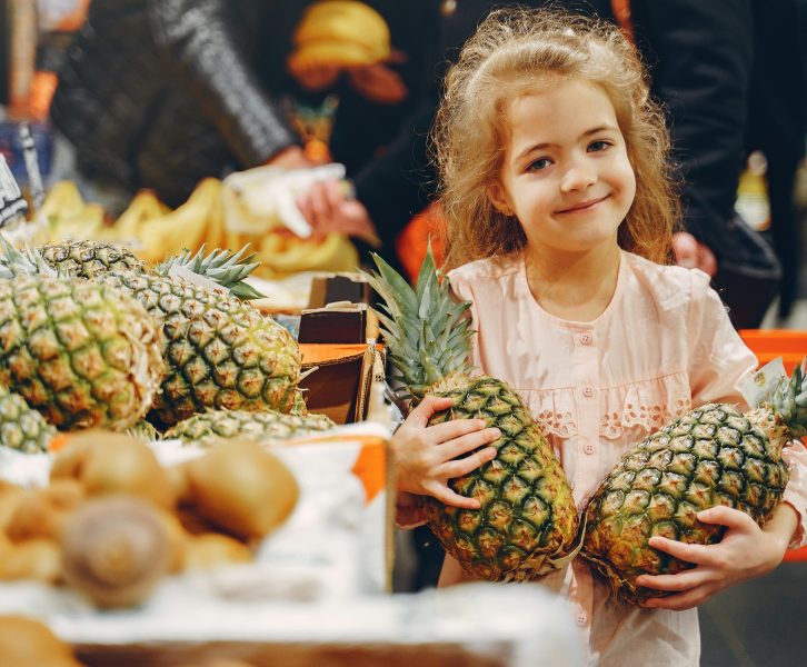 girl in grocery store with pineapples